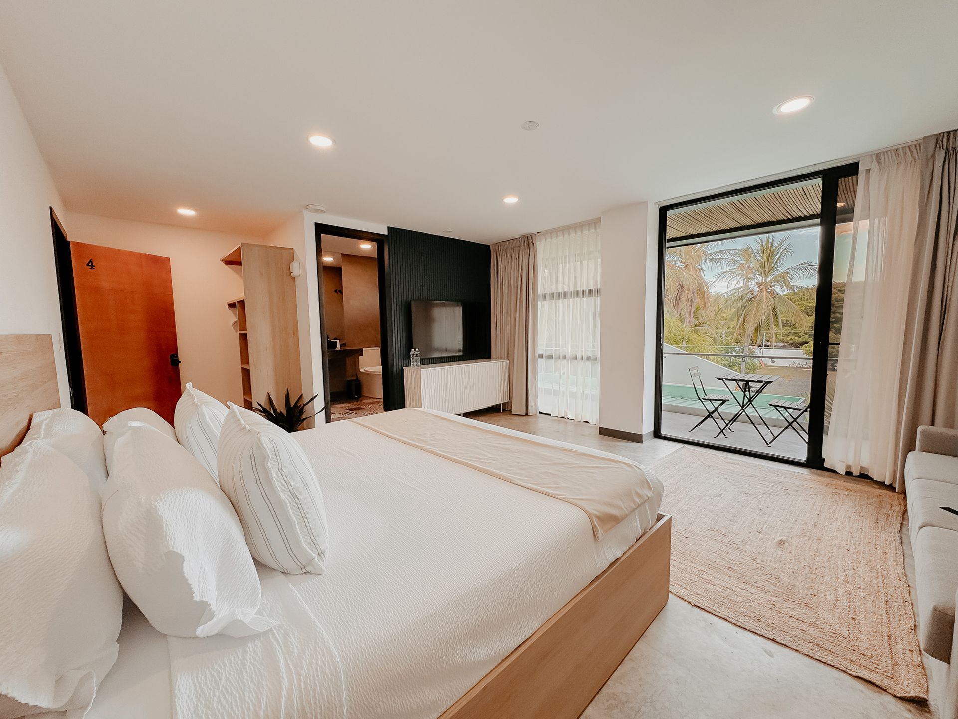 Habitación luminosa con cama, armario y puertas que dan a un patio y árboles.