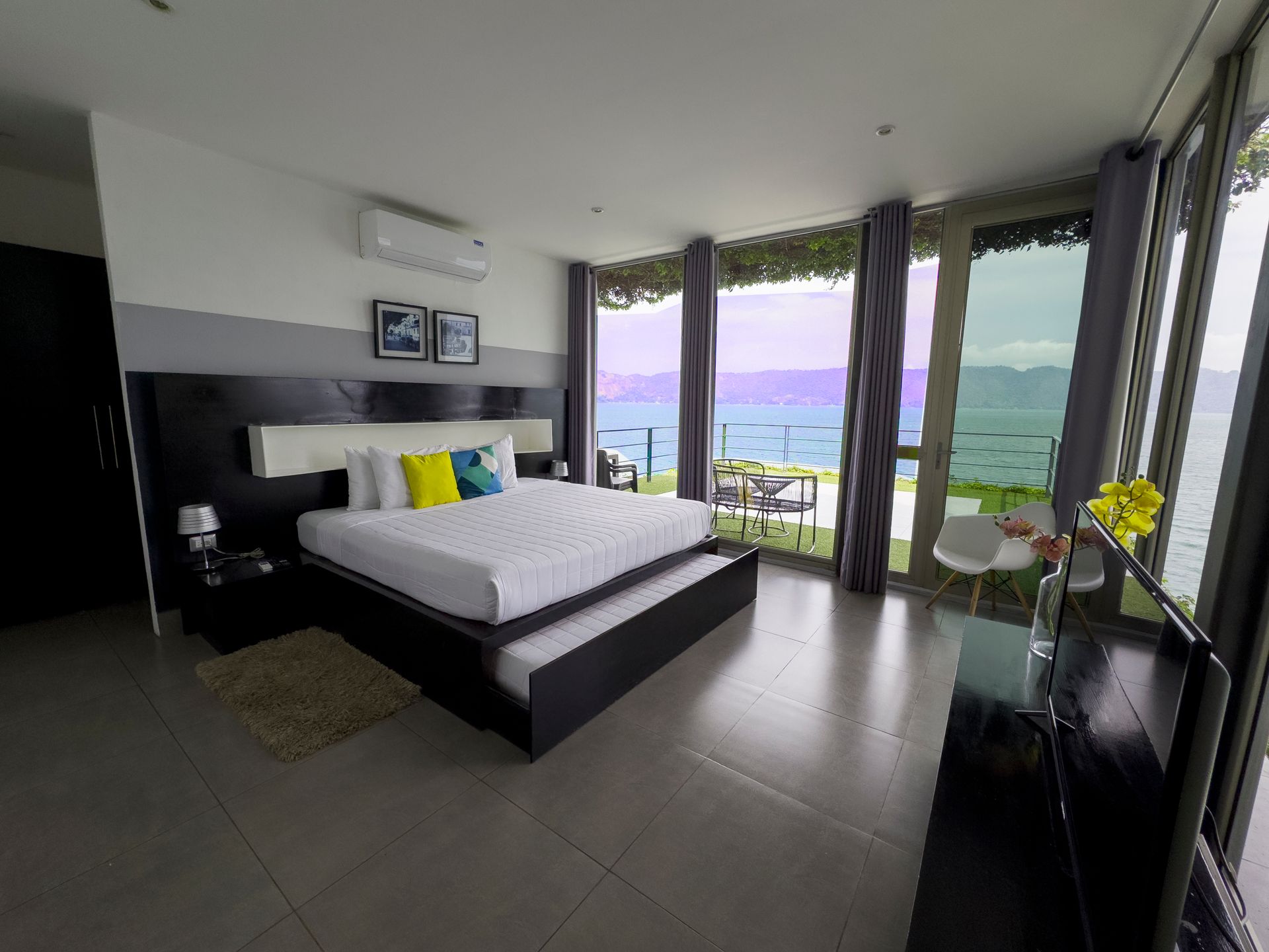 Habitación moderna con cama king size, ventanales del suelo al techo y vistas al océano.