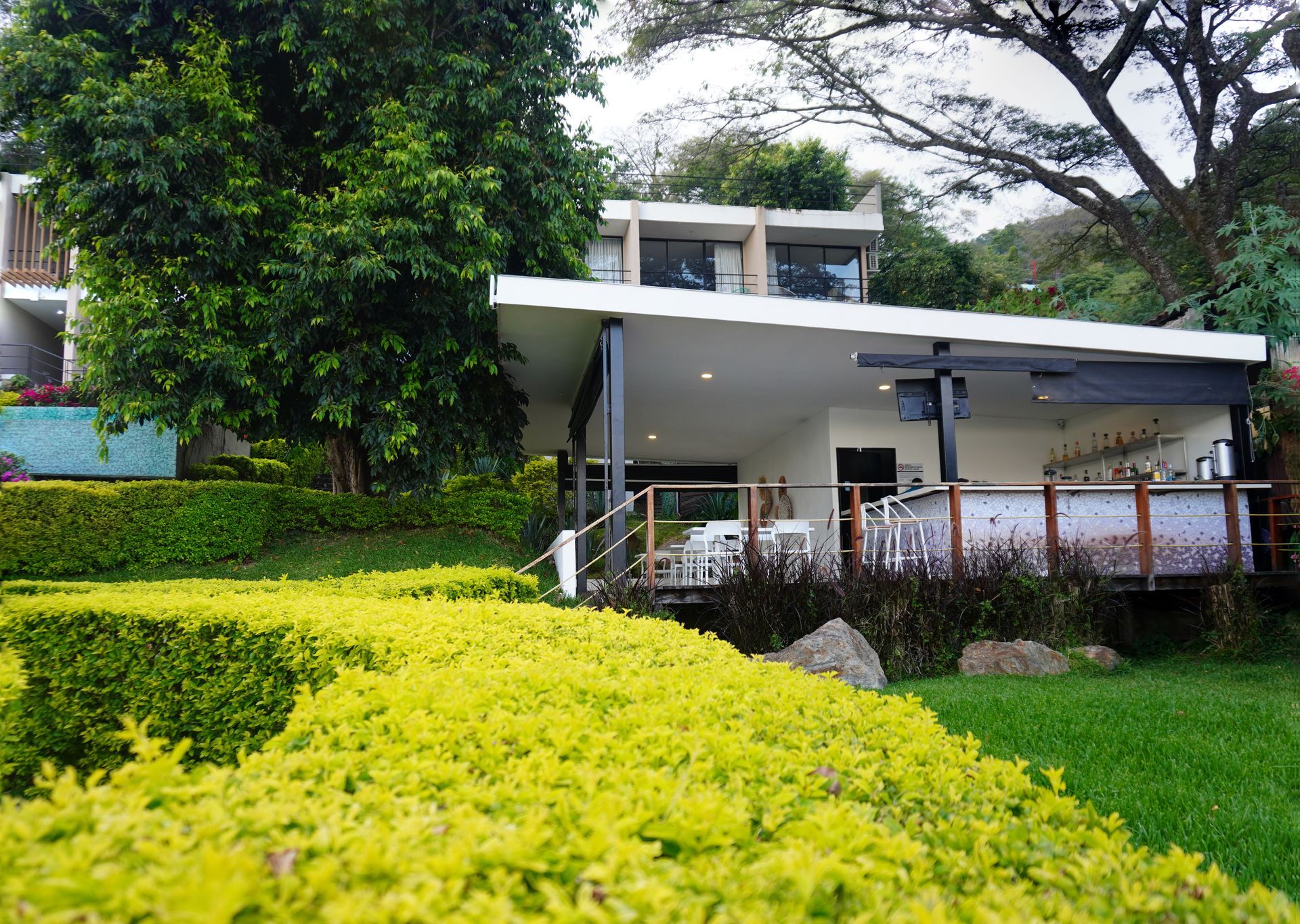 Casa moderna con cochera blanca, jardines exuberantes y grandes árboles en el exterior  en restaurante bistro hotel coatepeque