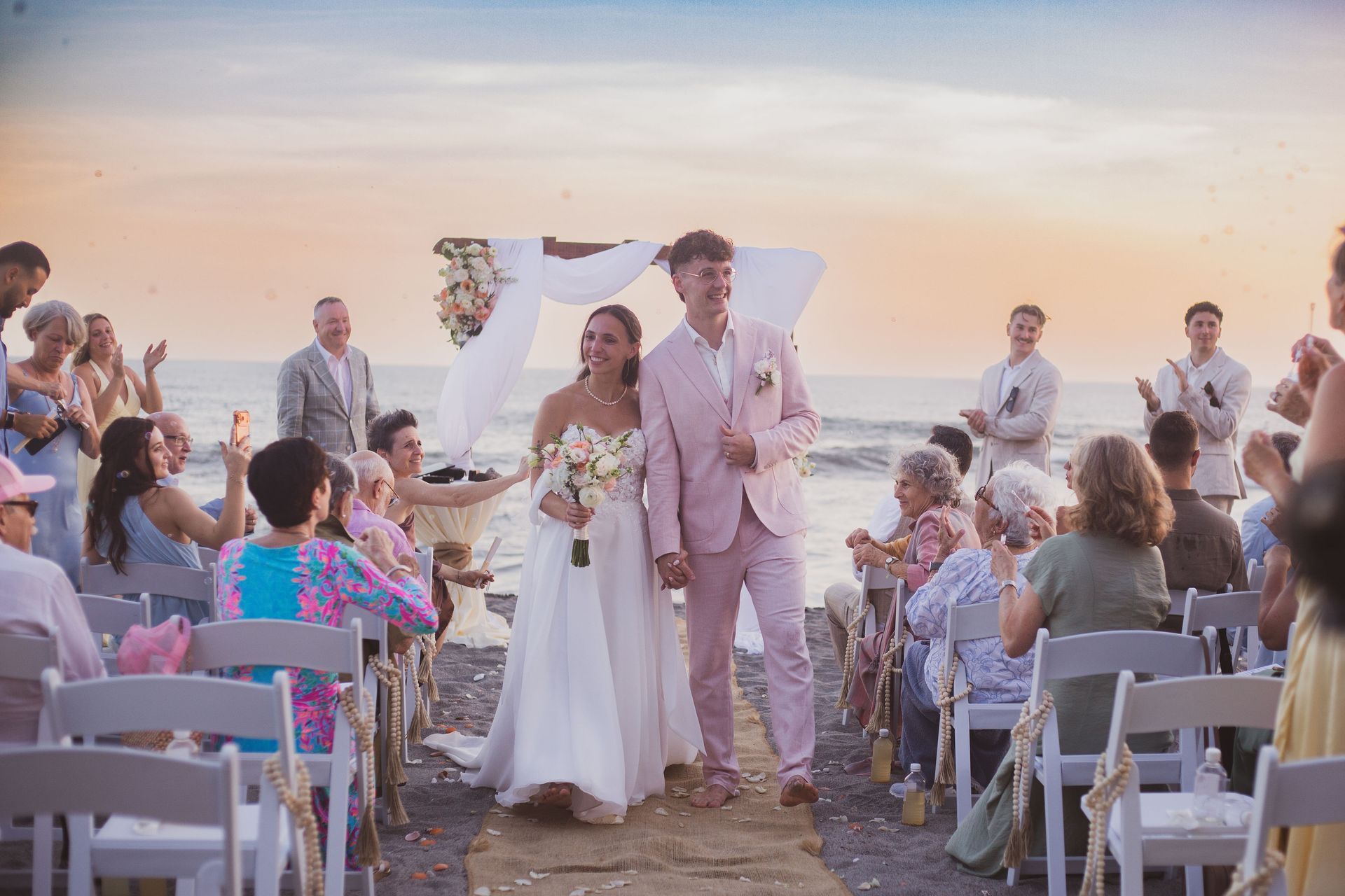 Novios caminando hacia el altar en una boda en la playa al atardecer en cangrejera cardedeu