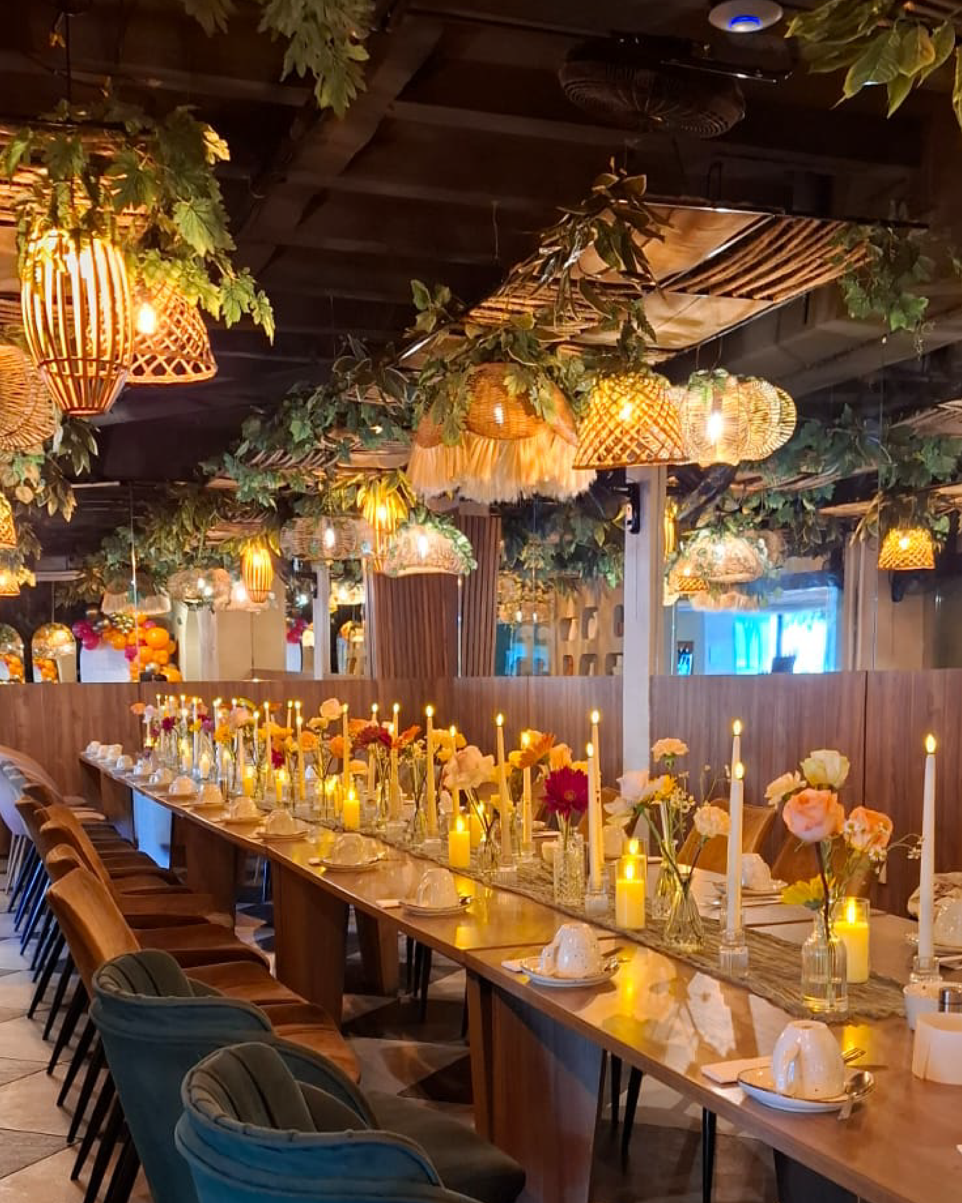 Larga mesa de banquete con centros de mesa florales y velas en un espacio interior rústico con iluminación cálida en silvestre san benito