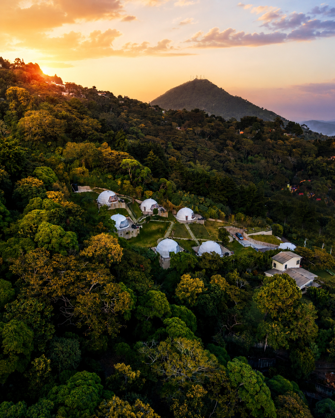 Puesta de sol sobre una ladera boscosa con tiendas de campaña blancas en forma de cúpula acurrucadas entre densos árboles verdes en cardedeu boquerón
