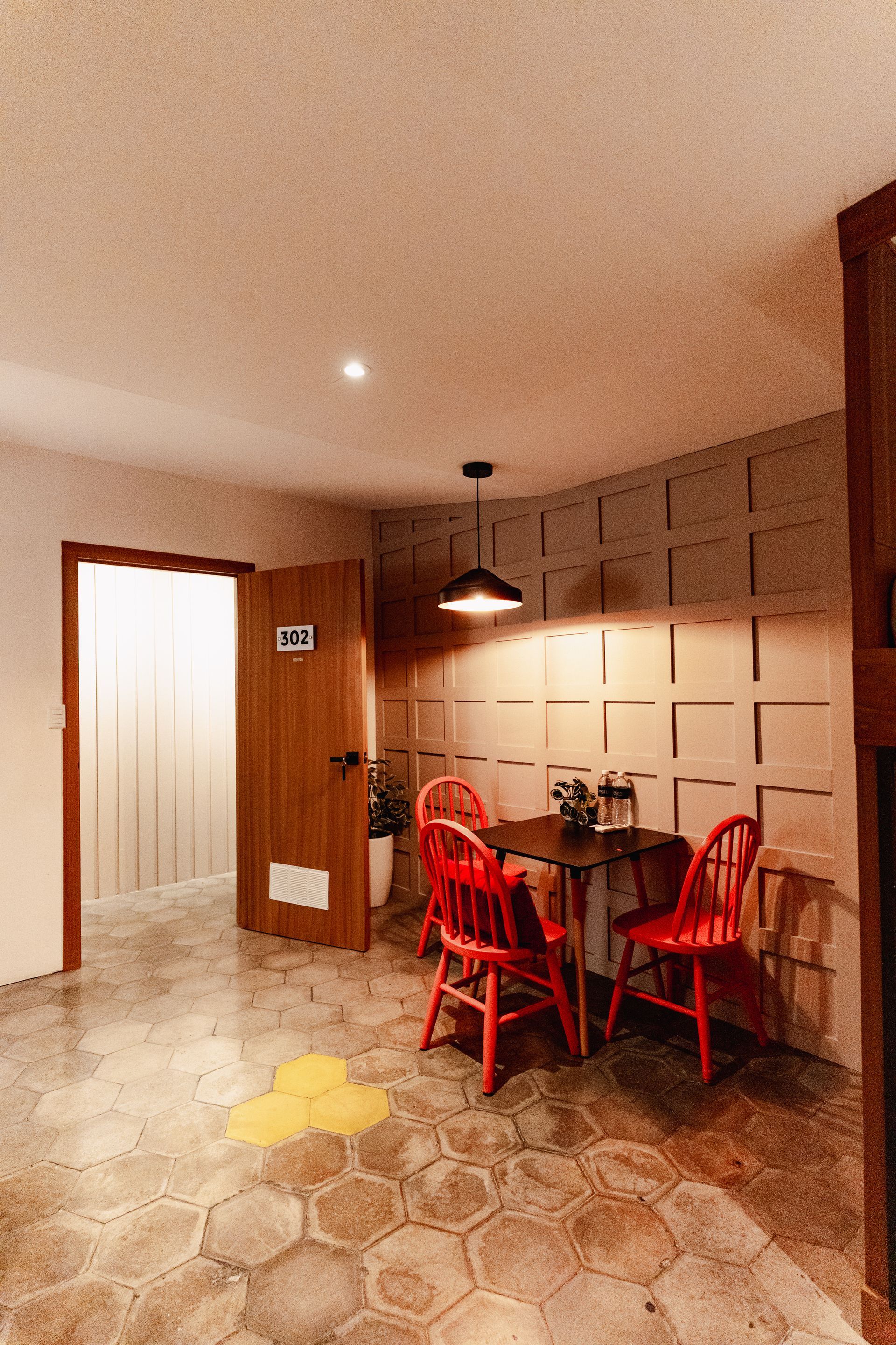 Cocina y comedor con sillas rojas, suelo de baldosas e iluminación cálida en hotel cardedeu express