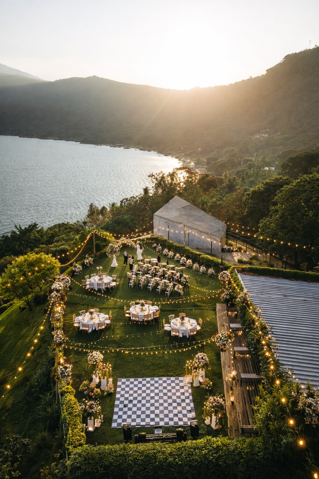 Elegante comedor al aire libre en una terraza cubierta de césped con vistas a un lago al atardecer en hotel cardedeu coatepeque