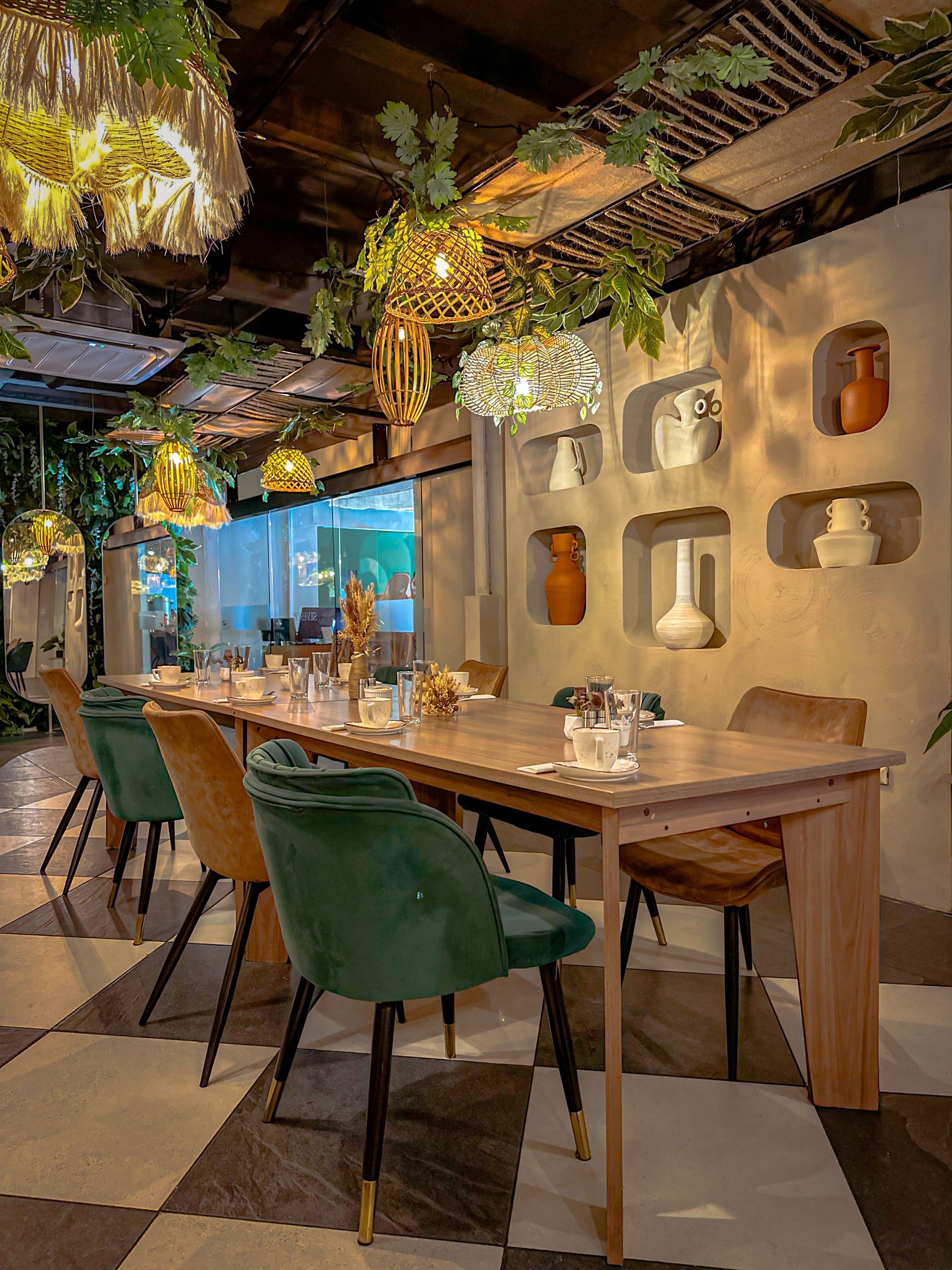 Acogedor comedor de restaurante con mesas de madera, sillas verdes, plantas colgantes y una iluminación ambiental suave en silvestre san benito