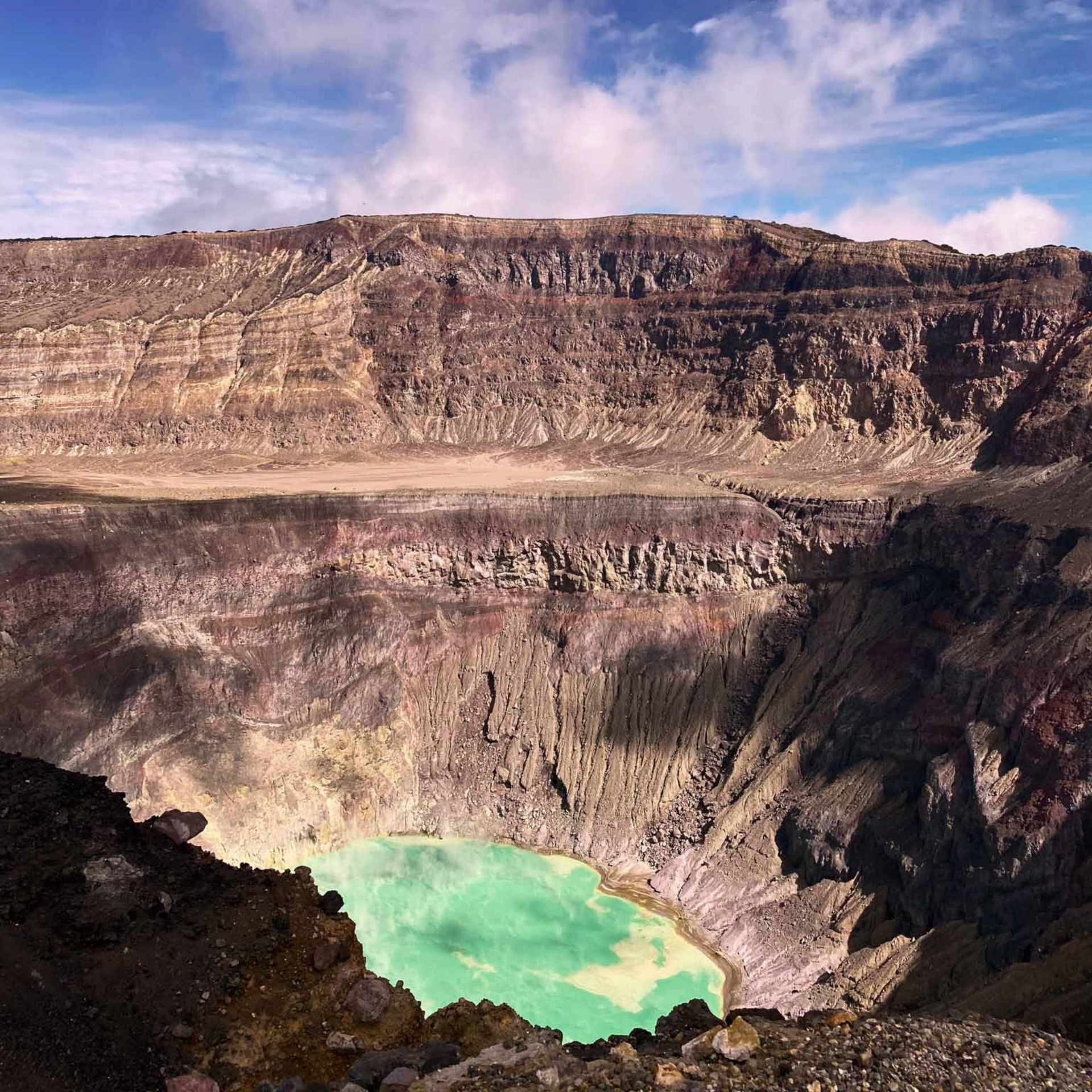 Lago de cráter con aguas turquesas bajo una escarpada caldera volcánica rocosa bajo un cielo azul en el volcan santa ana en el salvador