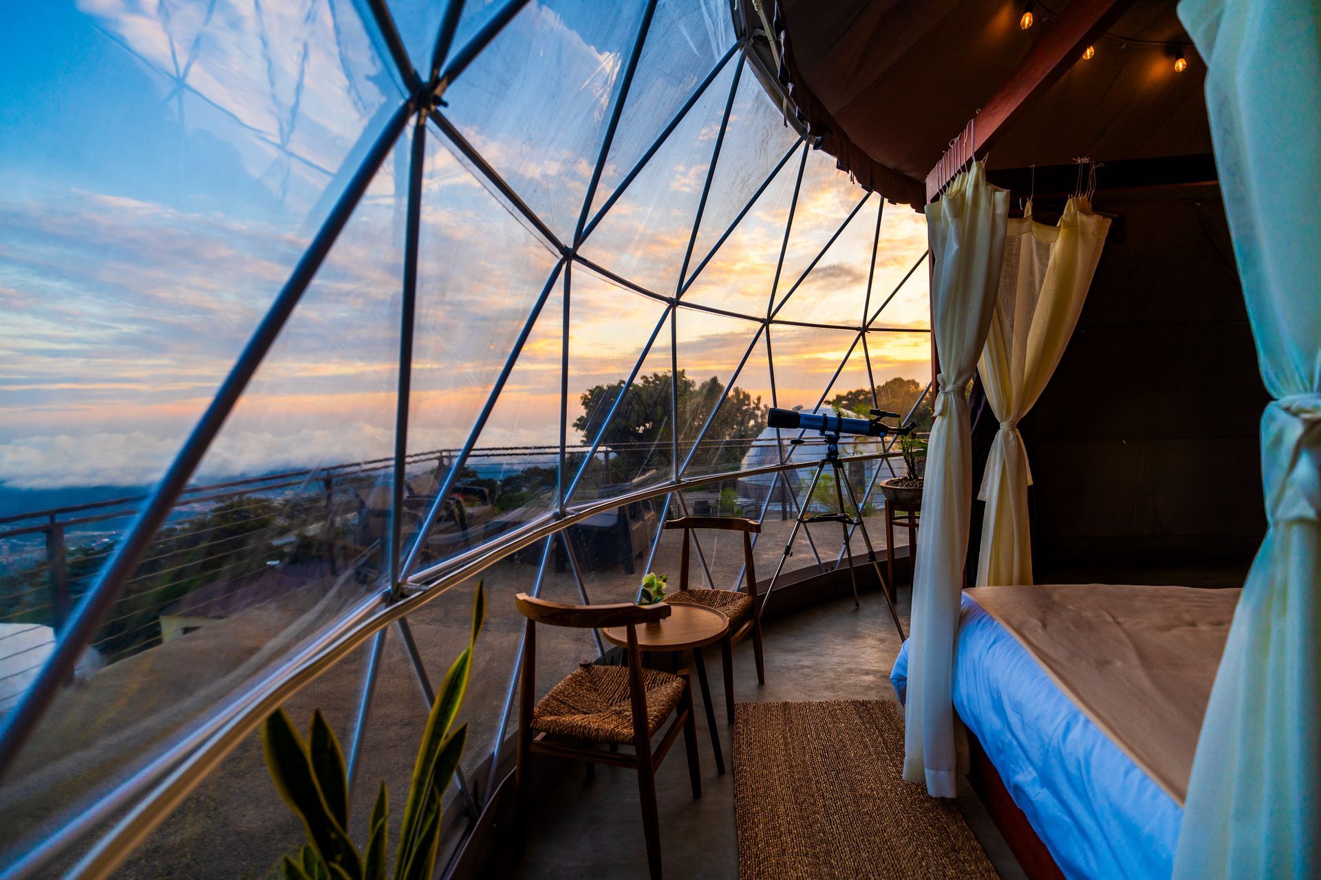 Acogedora tienda de campaña geodésica con forma de domo al atardecer, con cama, mesa y sillas con vistas a la costa el boquerón Cardedeu