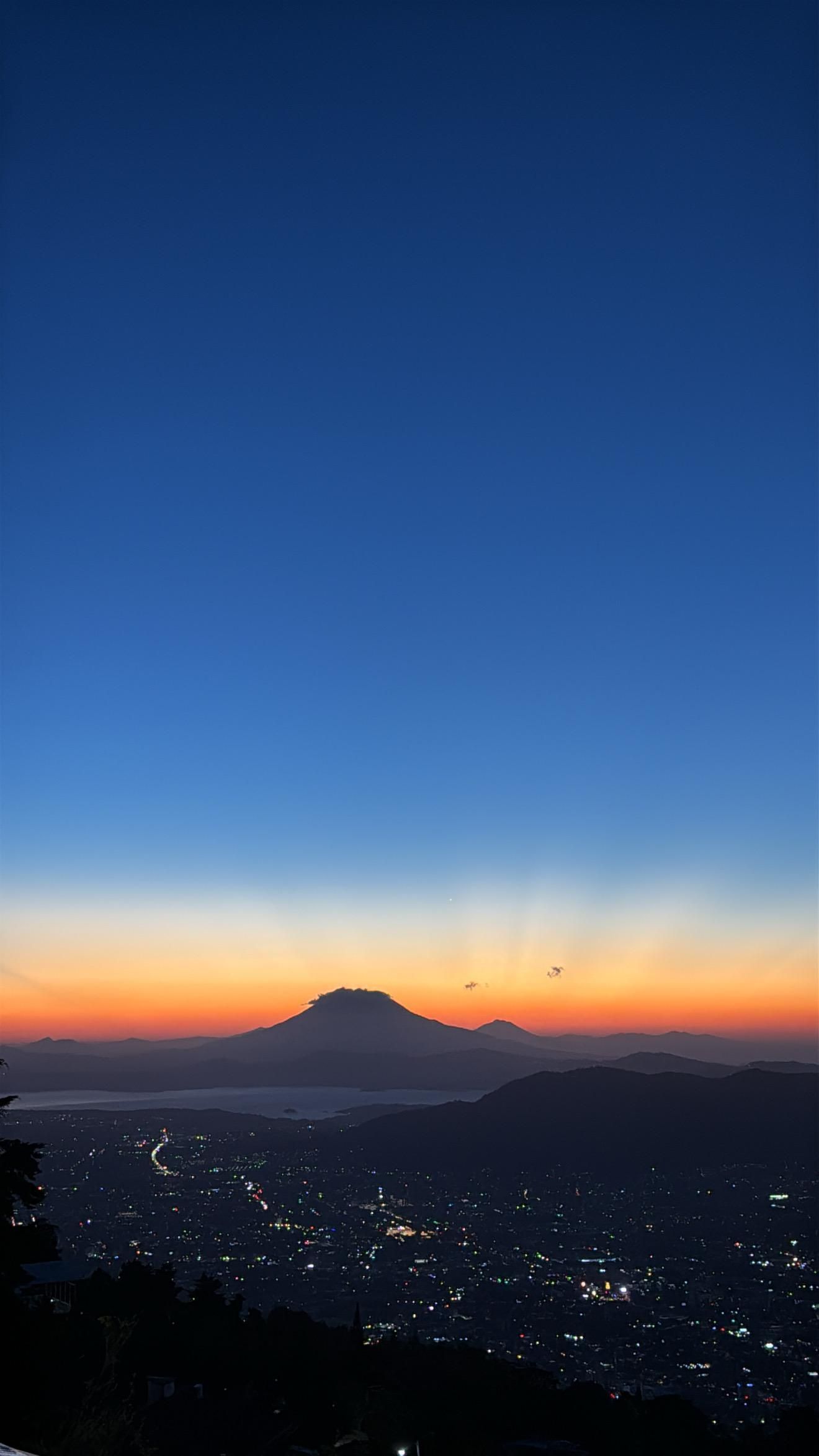 Horizonte crepuscular con una montaña recortada contra las luces de la ciudad y un cielo de puesta de sol de tonos naranja y azul el boquerón Cardedeu