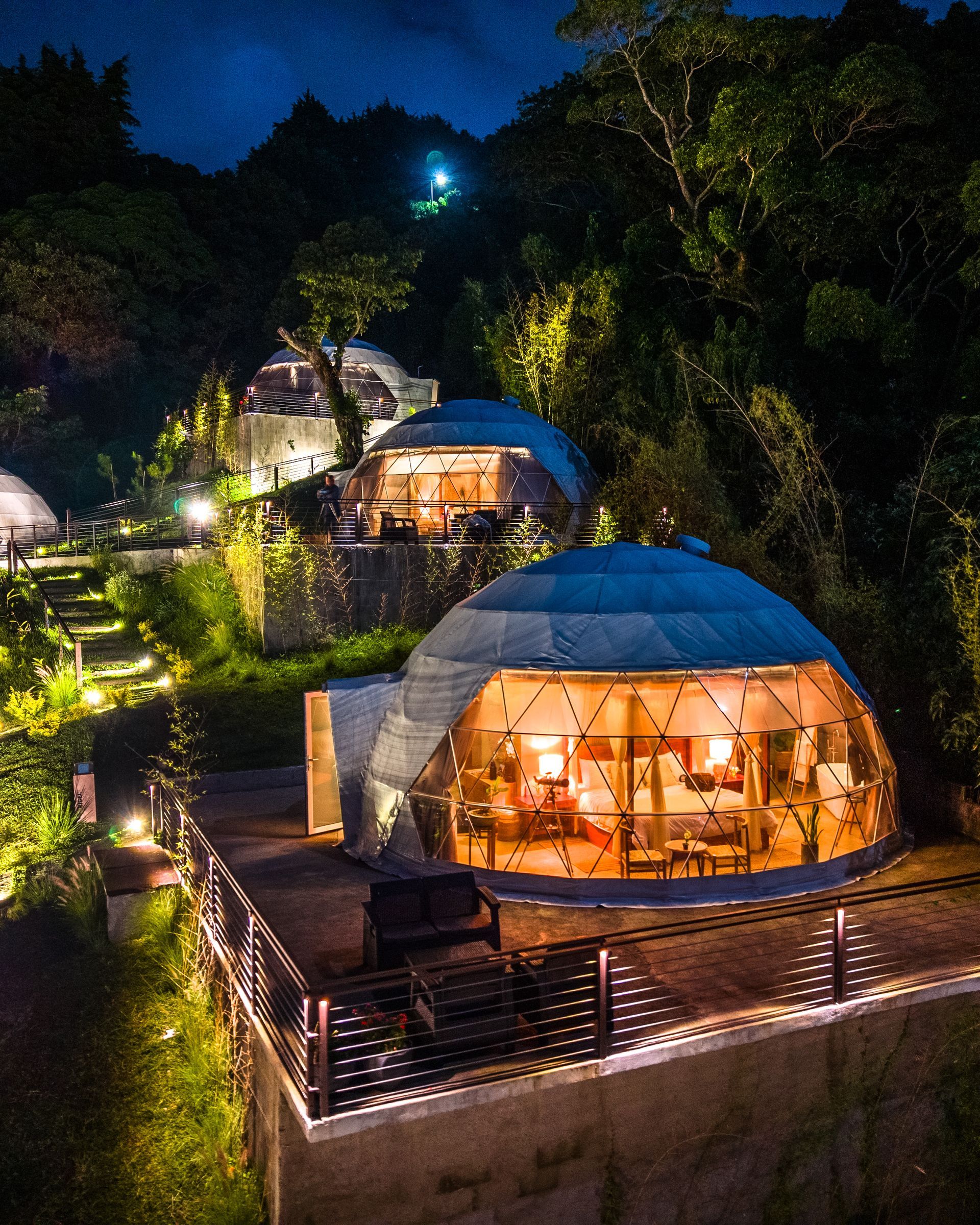 Cabañas con cúpula geodésica resplandecientes por la noche en un refugio en la ladera de una colina boscosa el boquerón Cardedeu