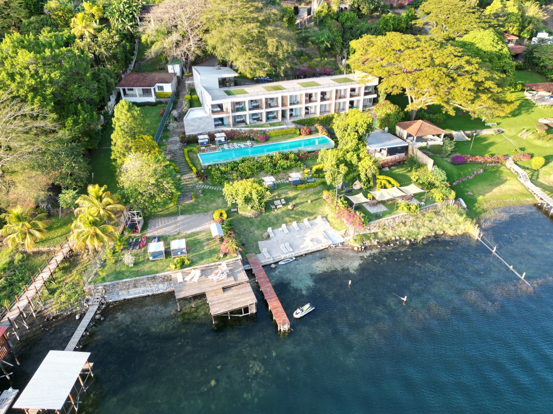 Vista aérea hotel cardedeu coatepeque, con piscina, muelle y frondosos árboles verdes.