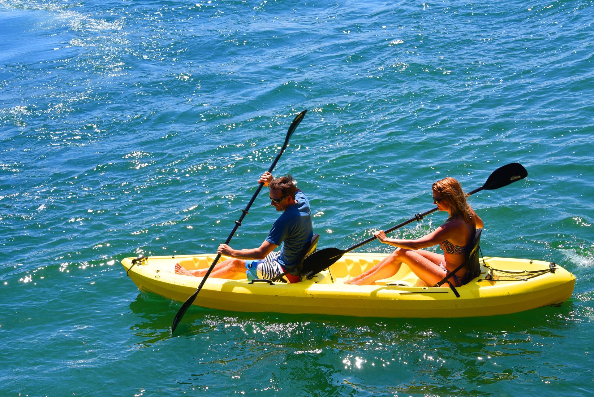 Dos personas practicando kayak en aguas azules en un kayak doble amarillo en cardedeu hotel coatepeque
