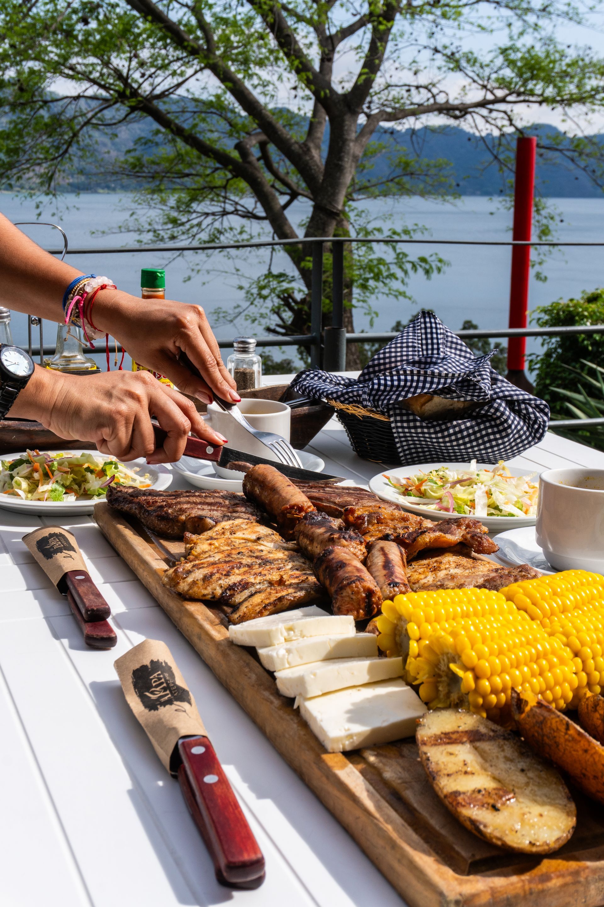 Mariscos a la parrilla y maíz en una mesa junto al lago, servidos al aire libre por personas que sirven la comida en restaurante pampa hotel coatepeque