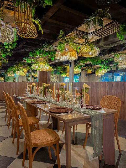 Mesa de comedor decorada bajo una exuberante vegetación colgante en un comedor con iluminación cálida en restaurante silvestre san benito
