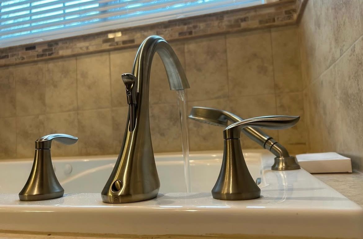 Close-up of a bathtub faucet with water flowing, set against a tiled wall.
