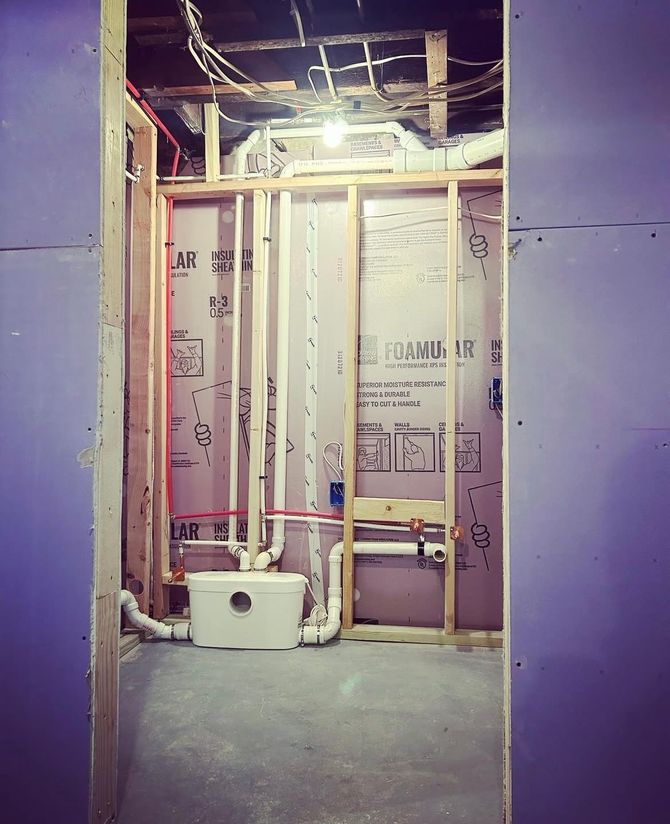 Pipes and plumbing, with red and white pipes secured to wood beams in a building’s ceiling.
