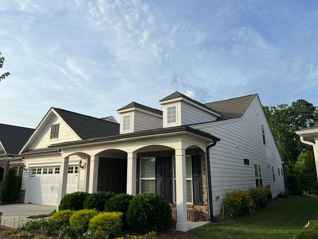 White suburban house with garage, front porch, and neatly trimmed bushes under a blue sky