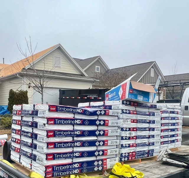 Stacks of TimberTech decking materials on a trailer in front of suburban houses.