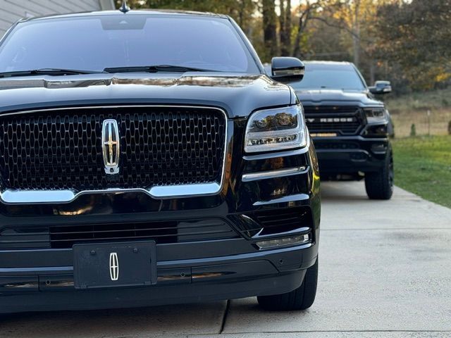 Two black Lincoln SUVs parked on a driveway, front view, with trees in the background
