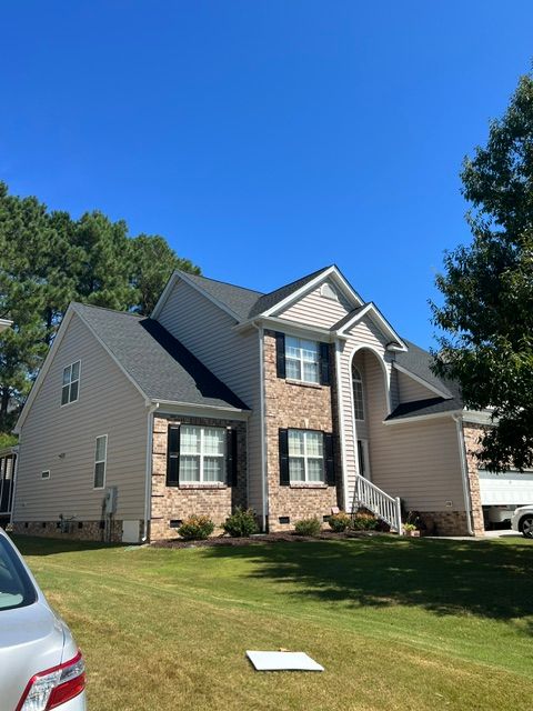 Two-story suburban house with brick and beige siding under a clear blue sky