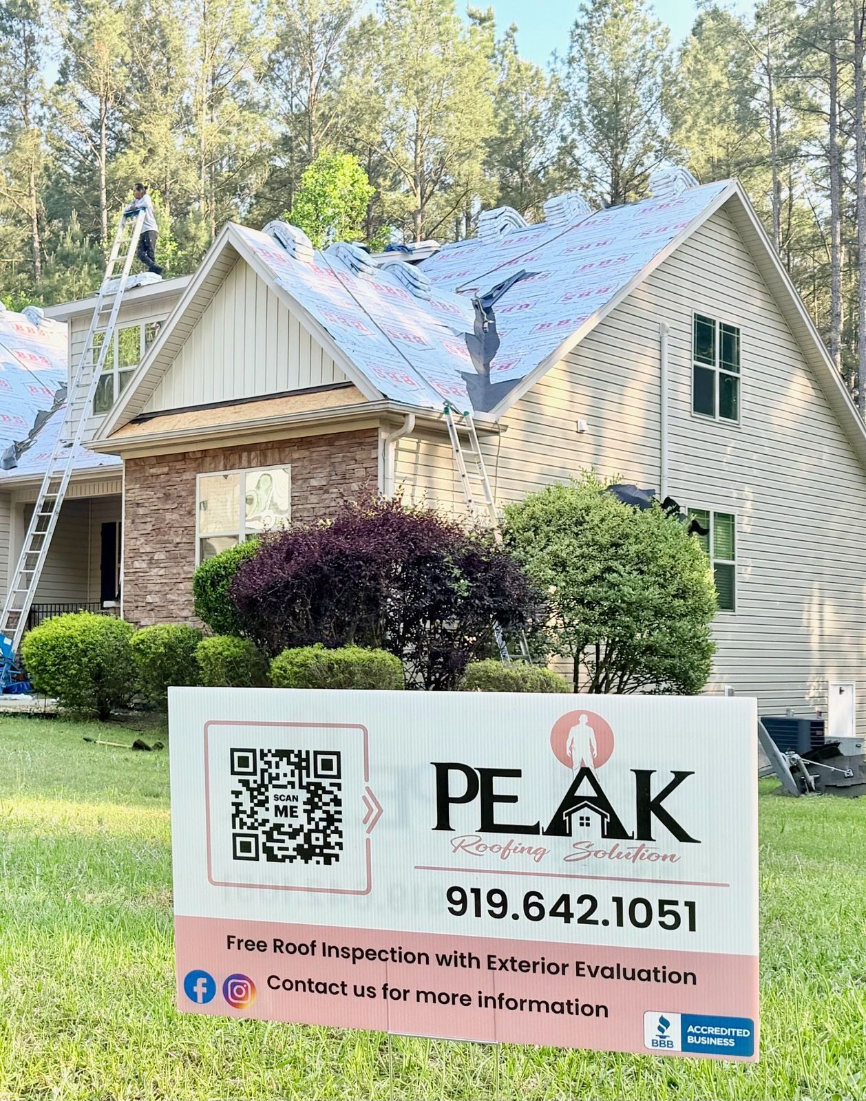 House with a PEAK lawn care sign in front, showing a QR code and phone number.
