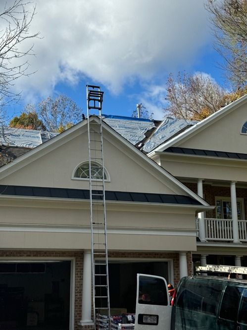 Ladder on garage roof with worker inspecting the ridge under a cloudy sky