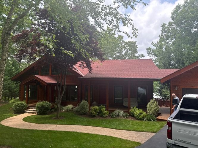 Single-story brick house with a red roof, front lawn, and driveway with a white pickup truck.