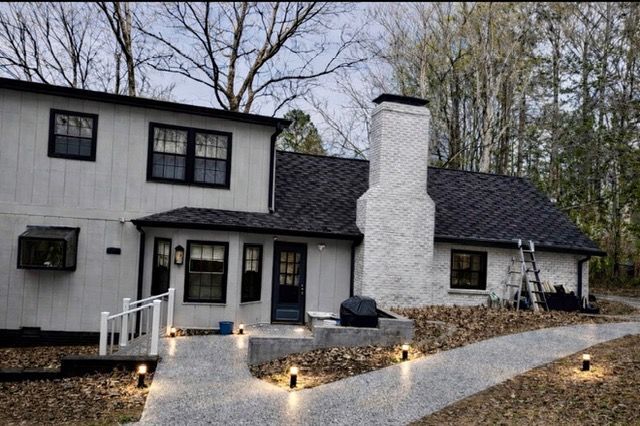 Modern two-story house exterior at dusk with lit pathway and white chimney