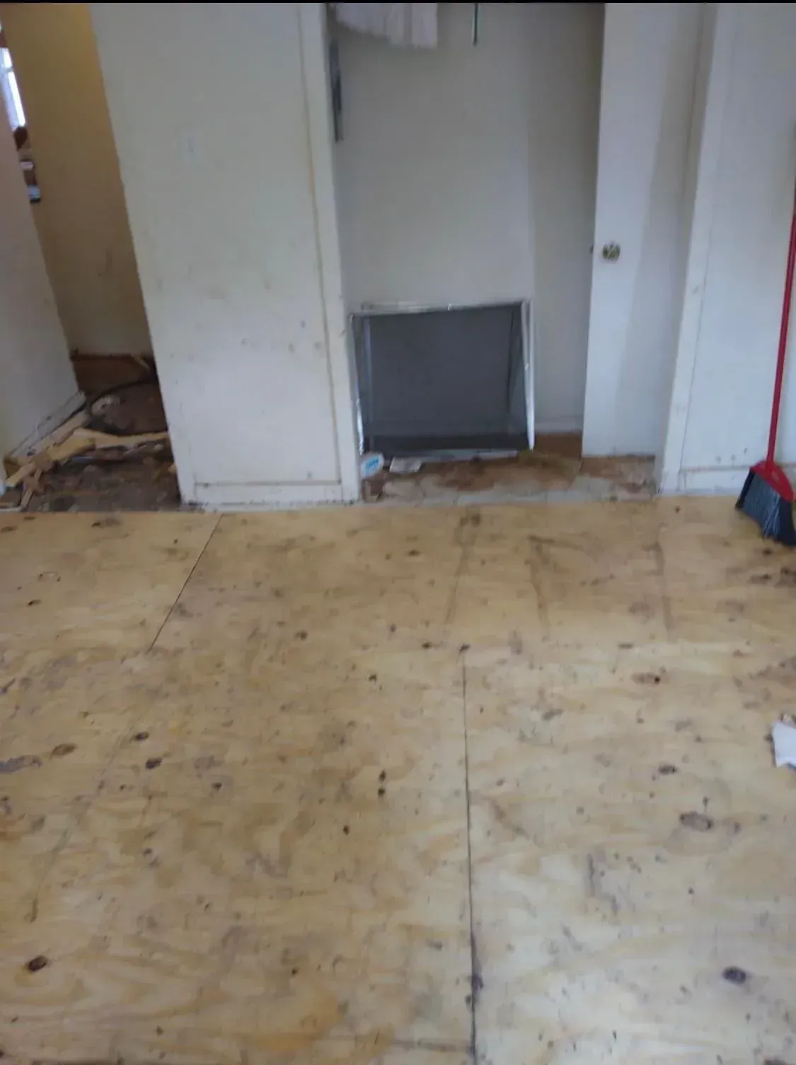 Bare room with worn tile floor, white walls, and an open doorway with a dark panel at the back.