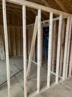 Framed interior room under construction with exposed wooden studs and rafters