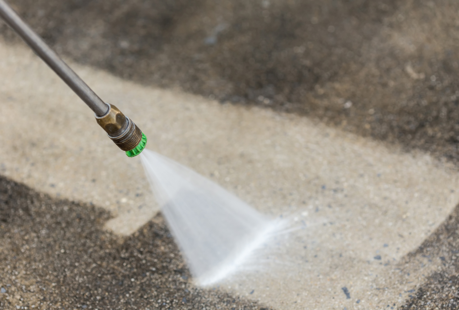 A pressure washer spraying water on a concrete surface, cleaning a dirty area.