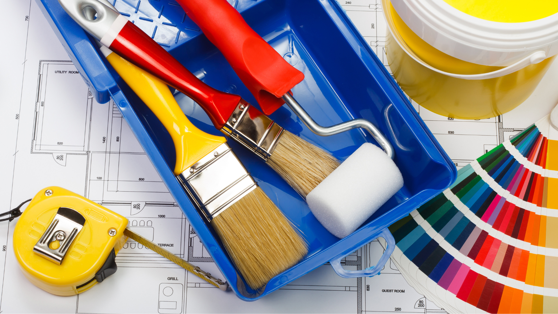 Paint supplies on a blueprint: paintbrushes, paint roller, paint can, color swatches, and measuring tape.