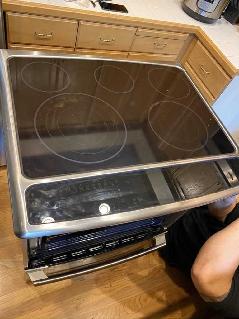 A person is working on a stove top oven in a kitchen.
