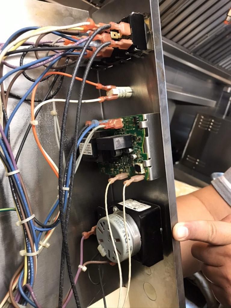 A person is working on a machine with a bunch of wires coming out of it.