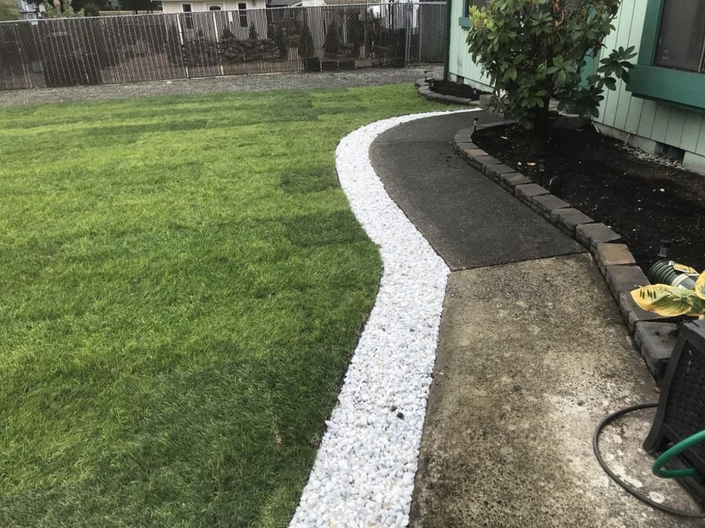 A lawn with a walkway lined with white gravel.
