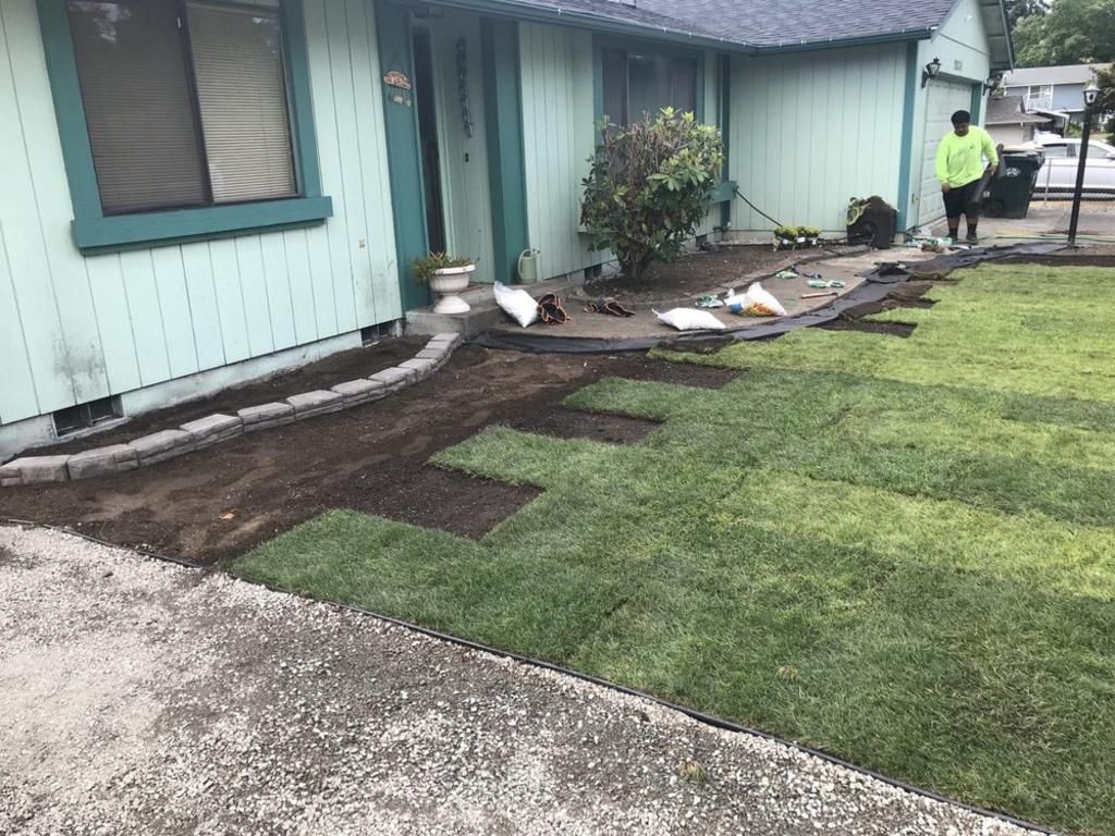 A man is working on a lawn in front of a house.