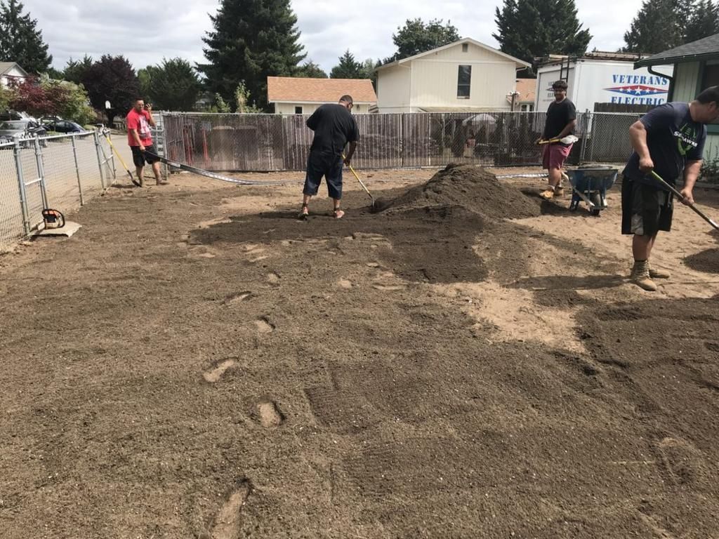 A group of people are working on a dirt field.