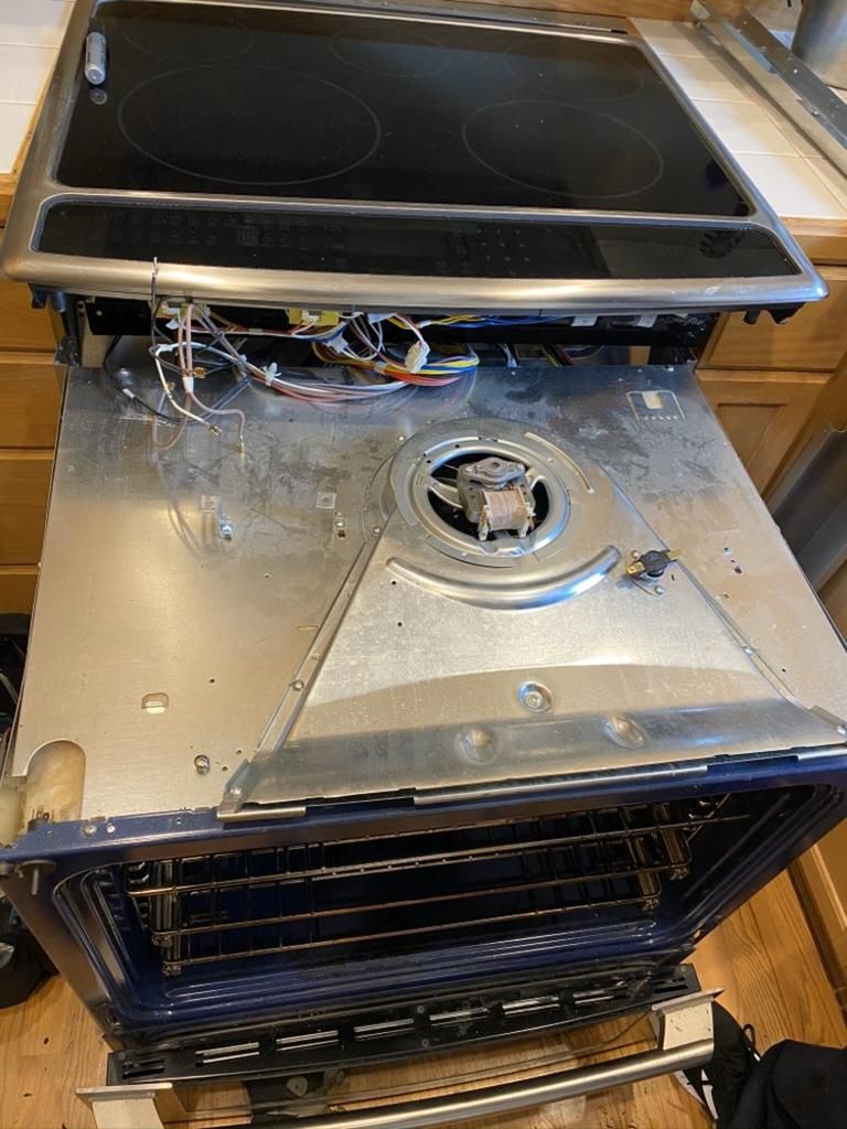 A stove top oven is being repaired in a kitchen.