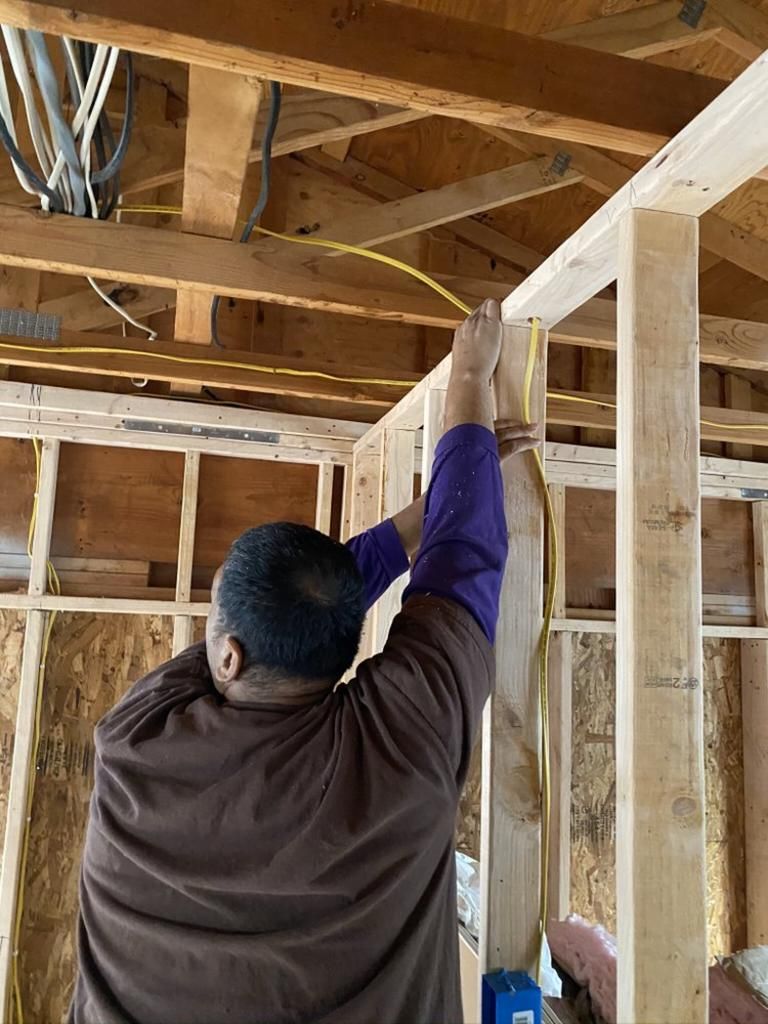 A man is measuring a piece of wood with a tape measure.