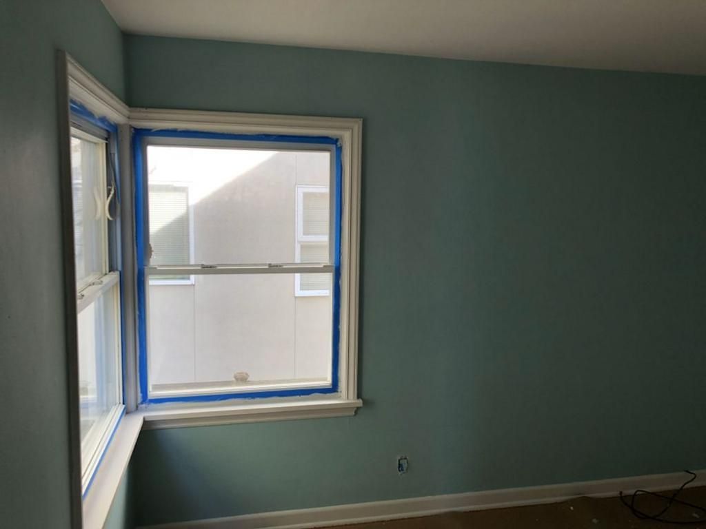 A room with blue walls and a window with blue tape on it