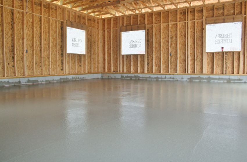 Empty room with unfinished wood framing and a smooth gray concrete floor