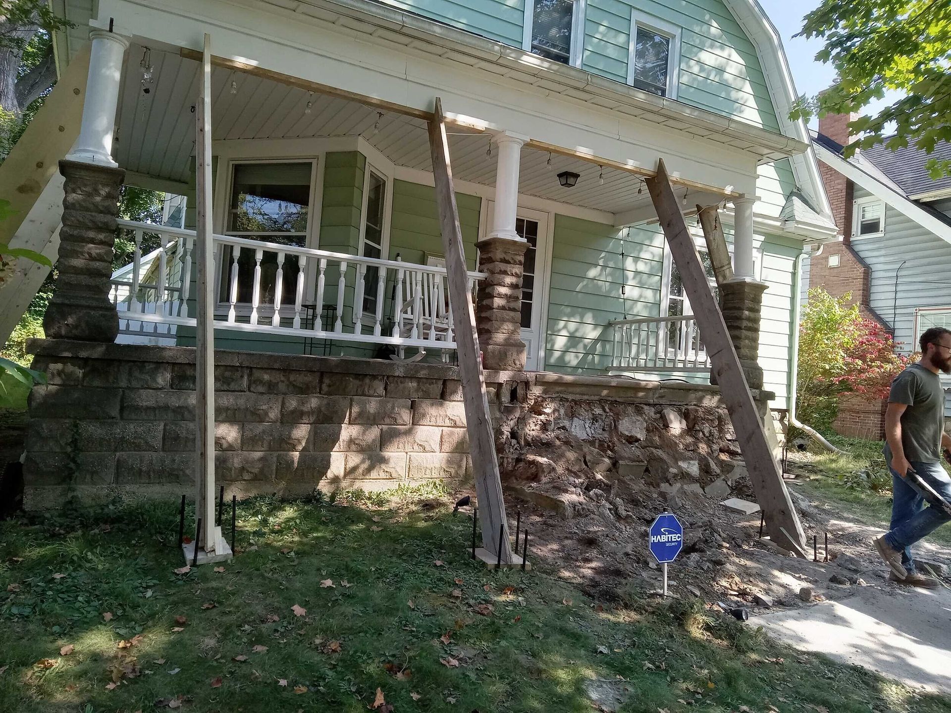 House porch with stone steps being repaired by two workers, one on each side of the stairway