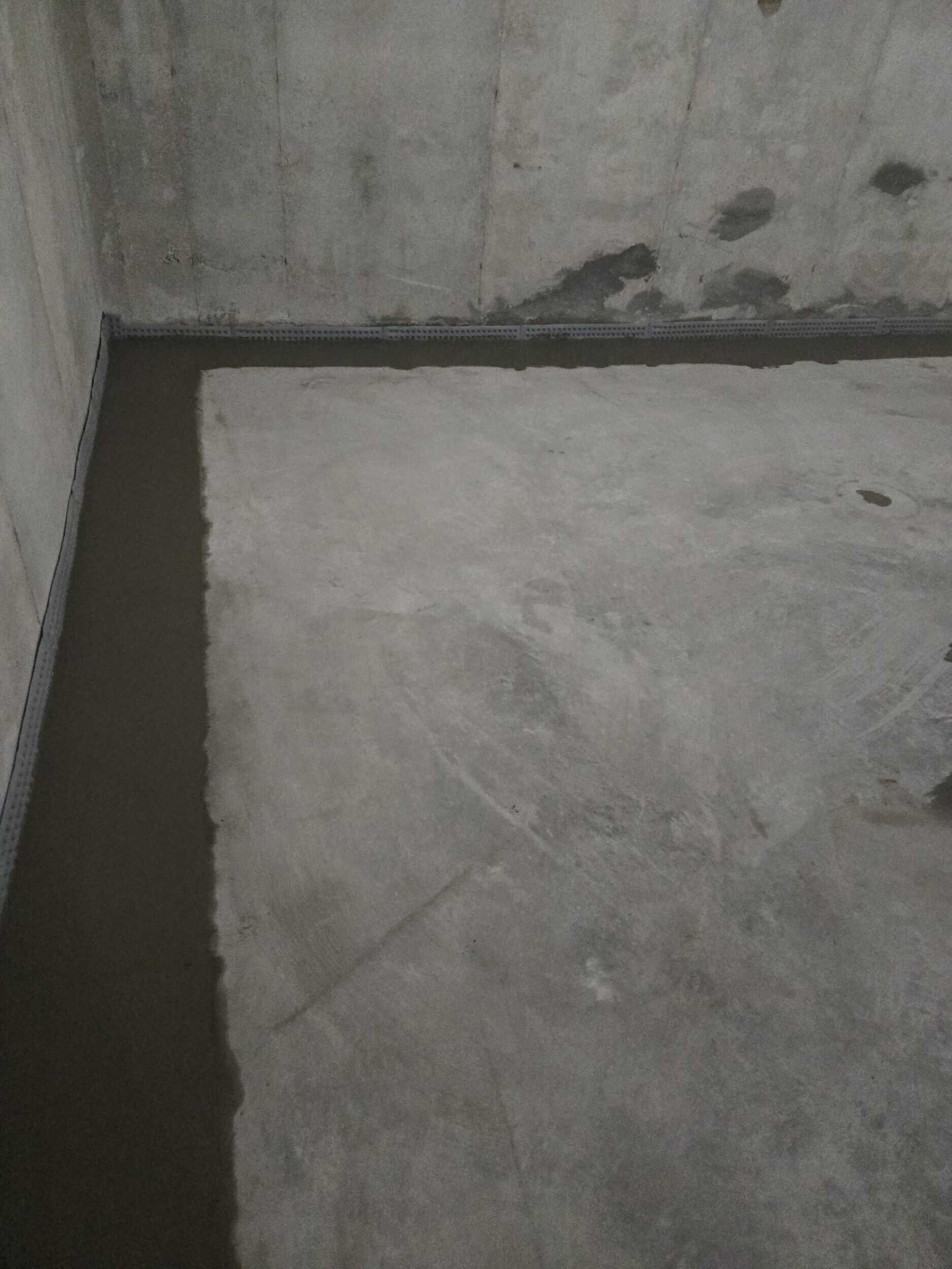 Concrete corner with dark water pooling along the wall and floor edge.