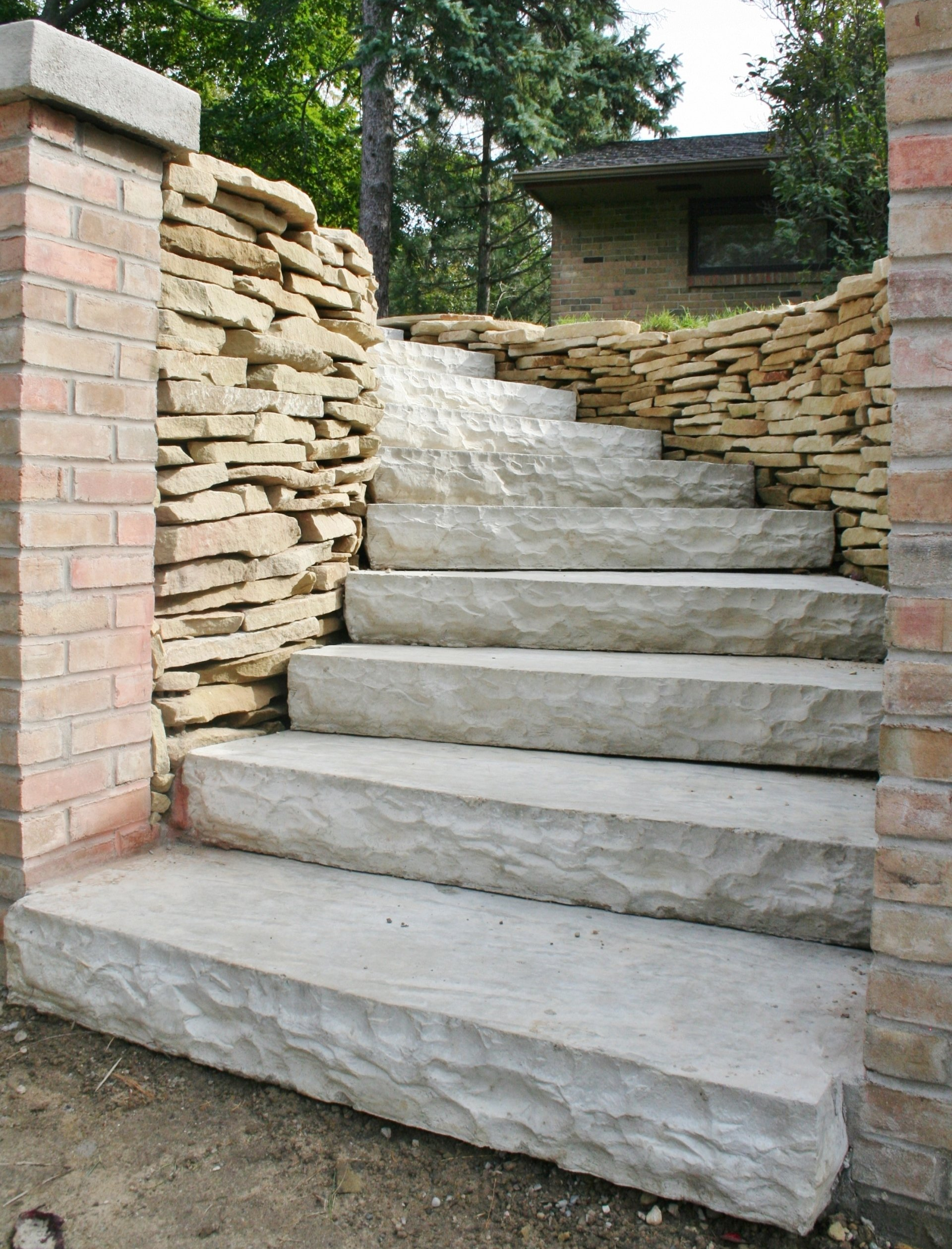 Stone steps with brick and stacked-stone walls leading up a landscaped outdoor path