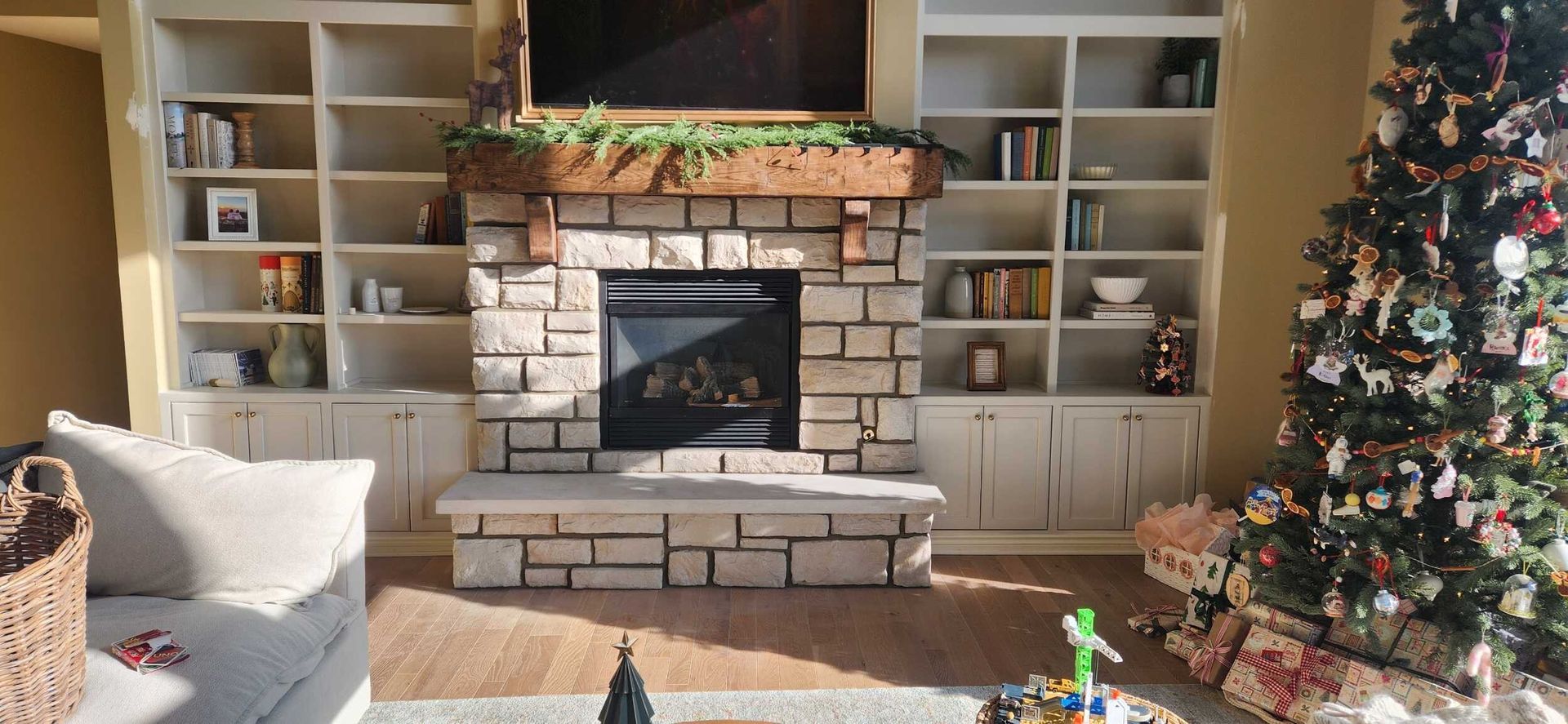 Cozy living room with a fireplace, built-in shelves, and a decorated Christmas tree