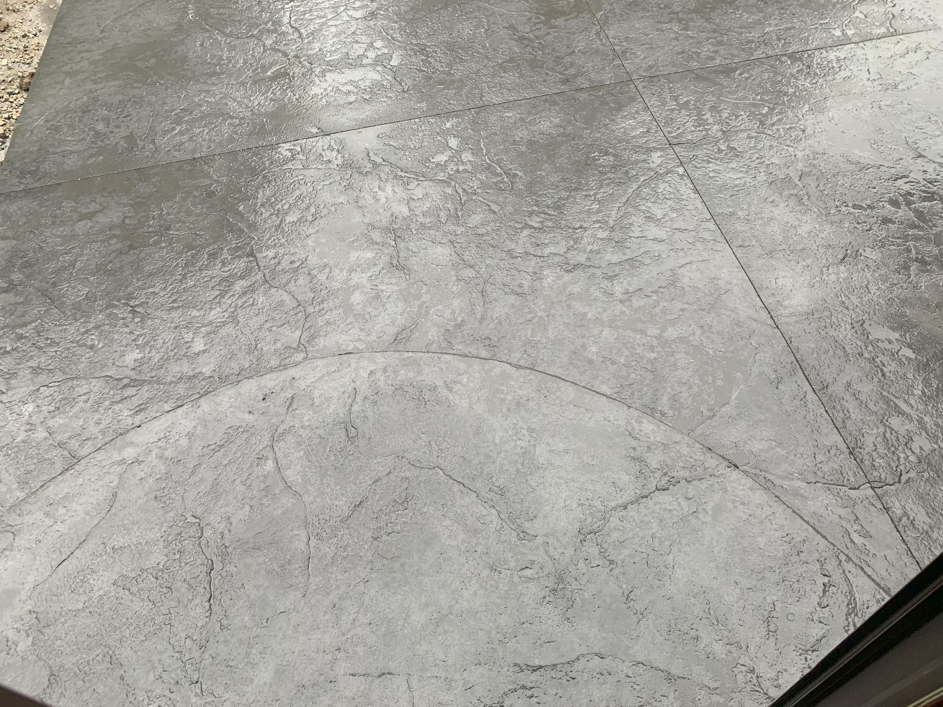 Close-up of a gray concrete sidewalk with faint circular and diagonal seams