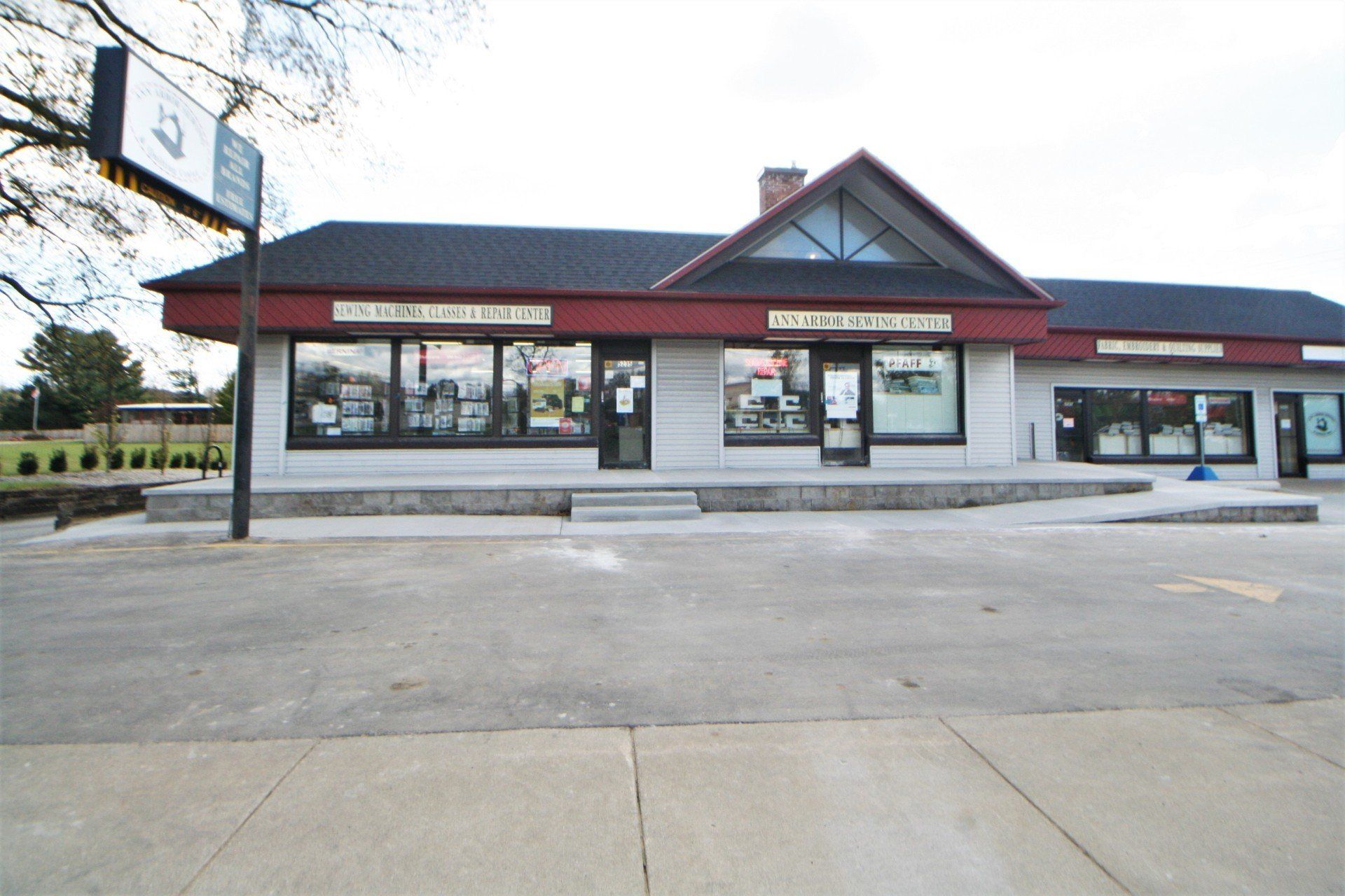 Small commercial strip mall with red trim and several storefronts, viewed across an empty parking lot.