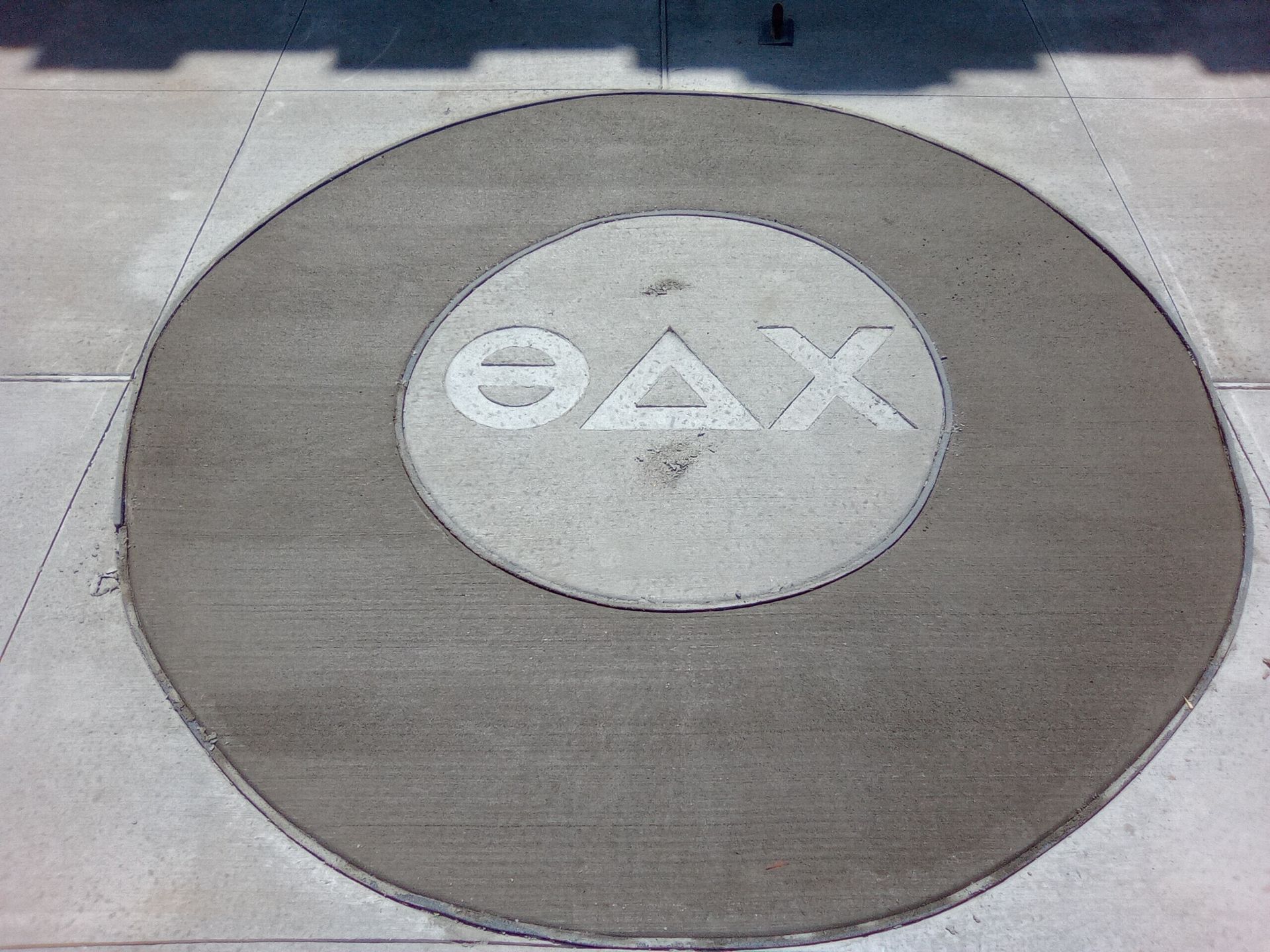 PlayStation button logo on a circular pavement marker with triangle, circle, X, and square symbols
