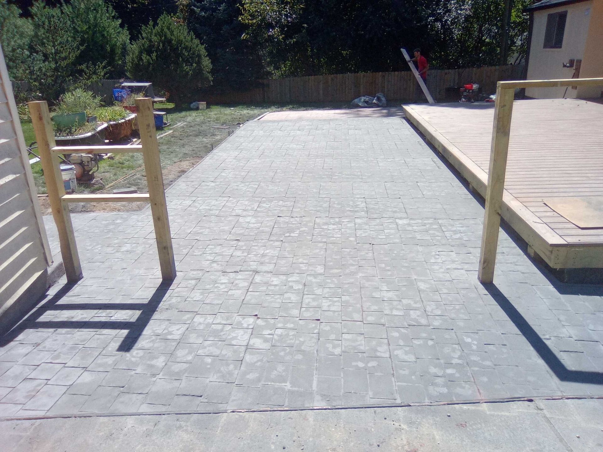 Stone walkway with wooden railings leading through a sunny outdoor yard