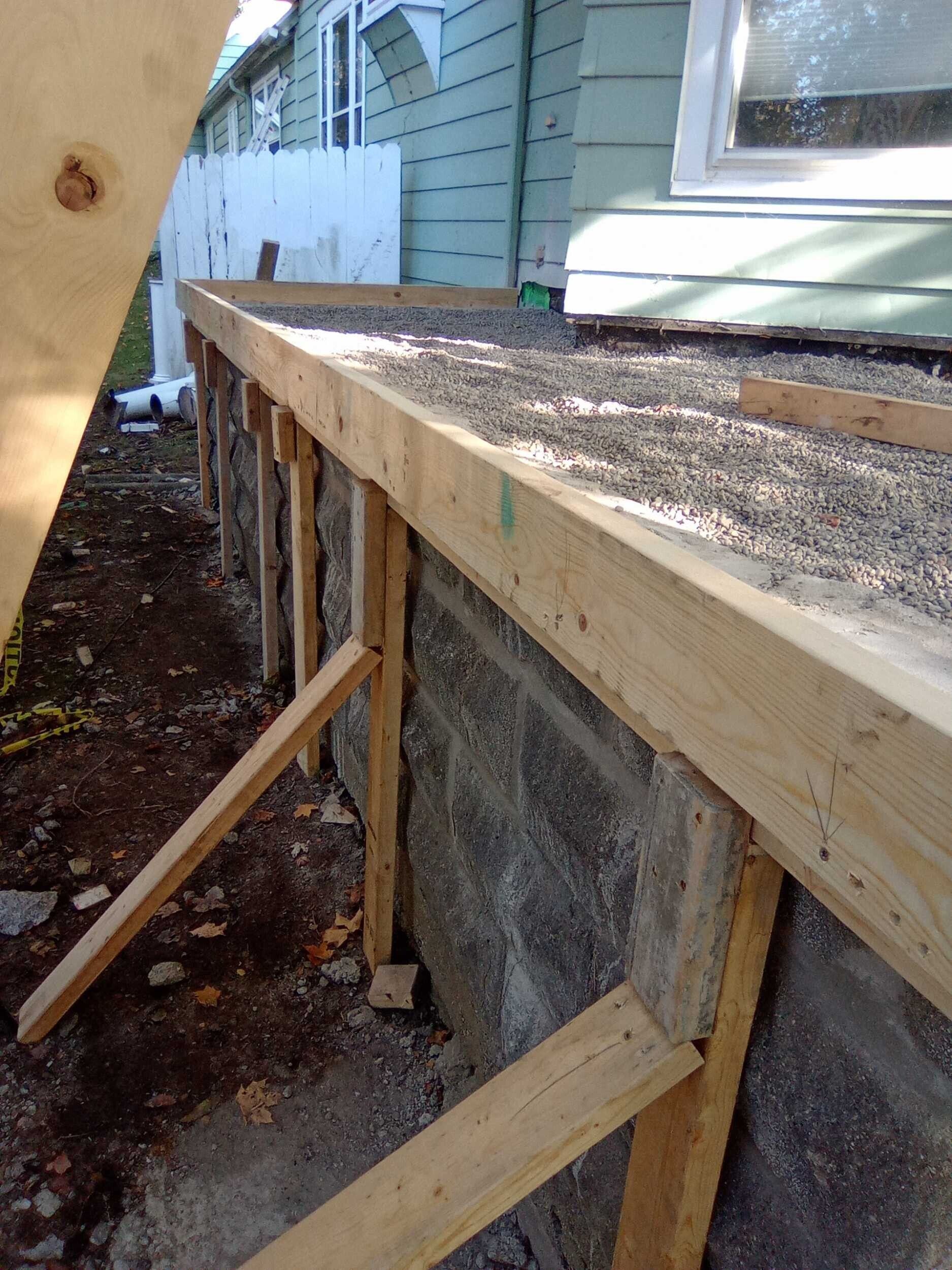 Construction framing and gravel-covered roof edge beside a house exterior.