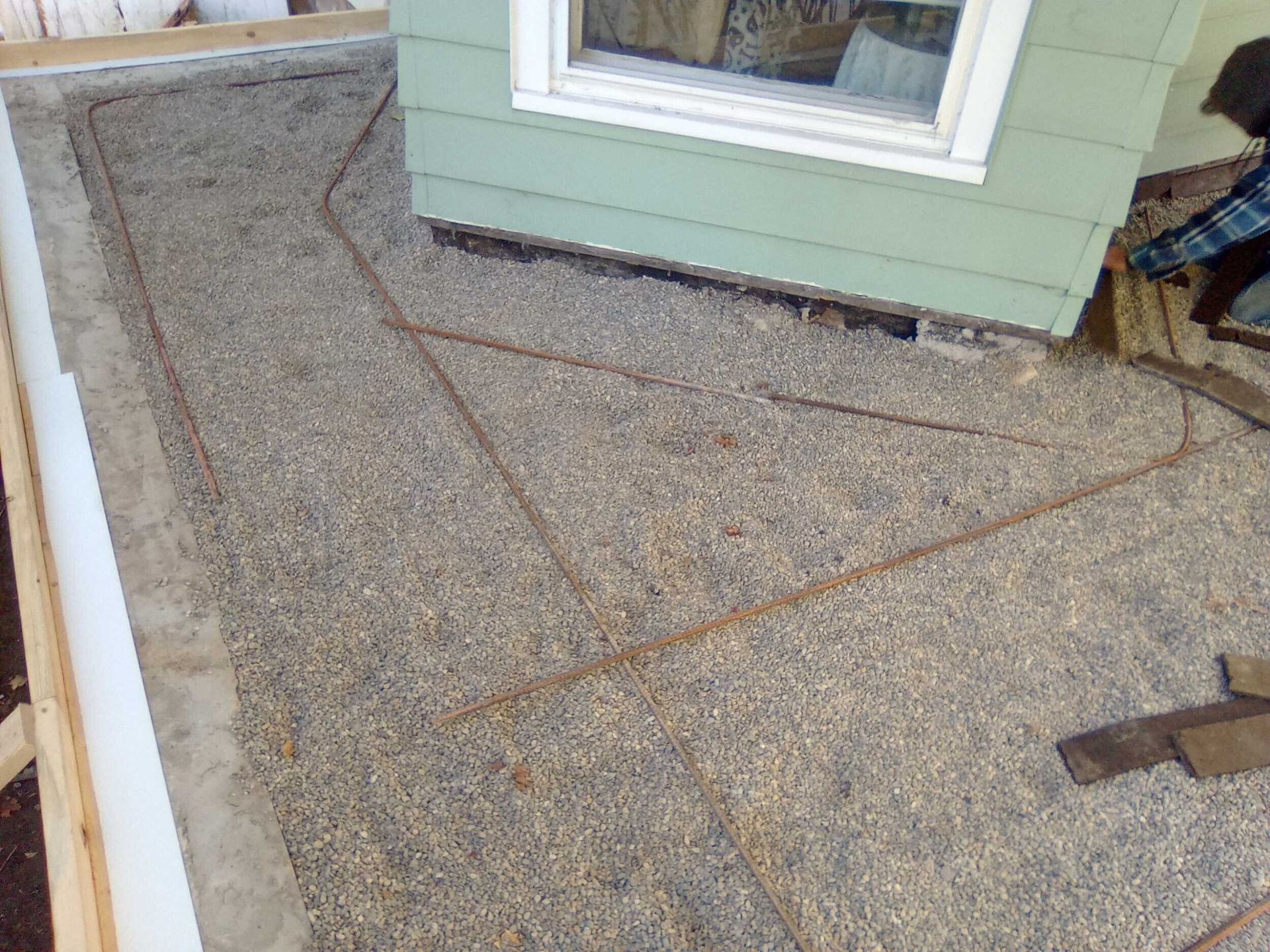 Roofing underlayment on a sloped roof beside a green house wall and window